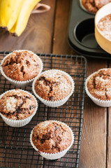 Homemade banana chocolate muffins sprinkled with sugar on a wooden background.