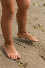Fototapeta na wymiar Bare feet of child playing on sandy beach