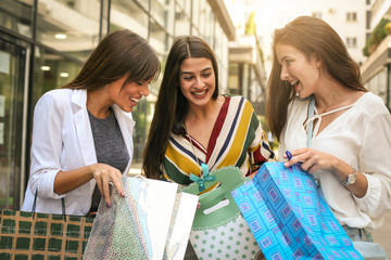 Girls watching their  new clothes. Tree best friend enjoying in spring day.