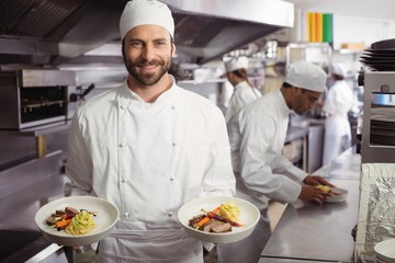Smiling chef holding delicious dish in kitchen