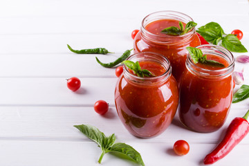 Spicy sweet tomato sauce with garlic, pepper and herbs in a glass jars.