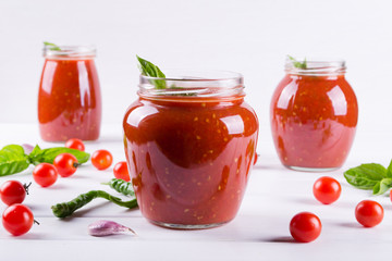 Fototapeta na wymiar Tomato sauce, ketchup in glass jar and ingredients on a white background 