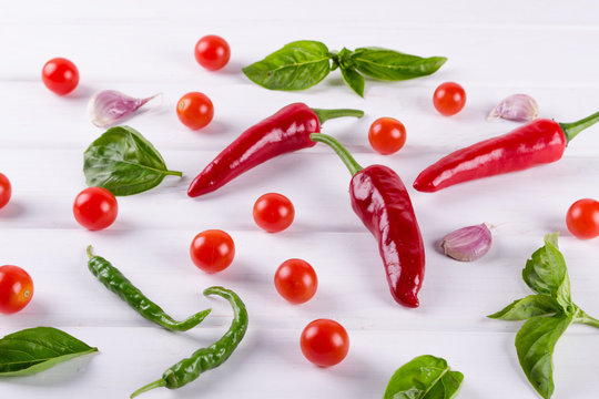 Red and green chili pepper, tomatos ,basil  herbs and garlic on white background