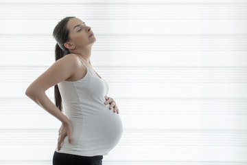 Young beautiful pregnant woman touching her belly with hands