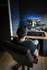 Gaming room.Young man playing video games on computer with joystick in a dark room 