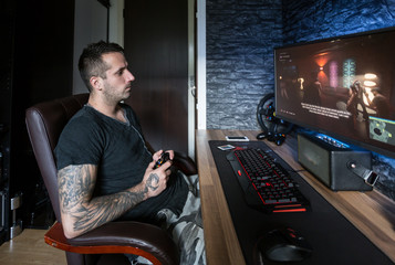 Gaming room.Young man playing video games on computer with joystick in a dark room 
