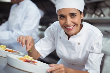 Female chef garnishing food in kitchen at restaurant