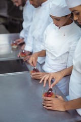 Chefs finishing dessert in glass at restaurant