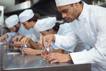 Chefs finishing dessert in glass at restaurant