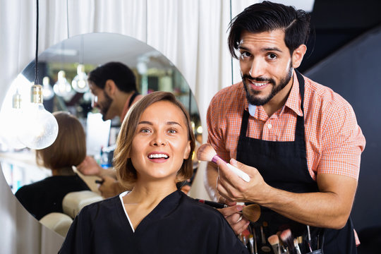 Man makeup artist applying cosmetics for woman