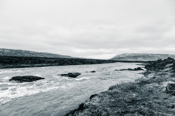 Water of stormy mountain river from waterfall - beautiful part of stony rocky desert landscape of Iceland. Toned