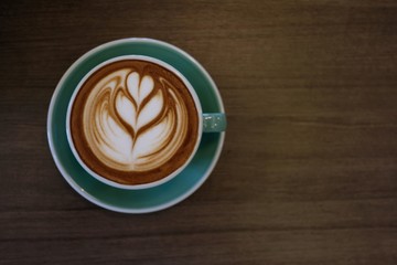 Cup of hot latte art coffee on wooden table.