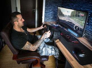 Video gamer.young man playing video games on computer in a dark room using steering wheel