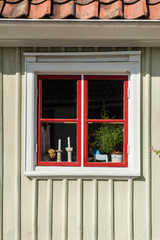 Wooden house with small red window, with curtains and flowers in scandinavian style. Sweden, Scandinavia, Europe.