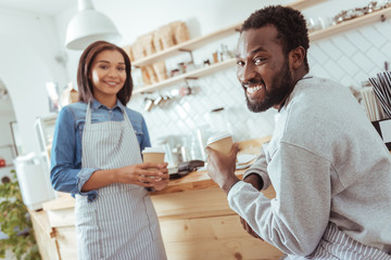 Joyful baristas posing while having coffee break