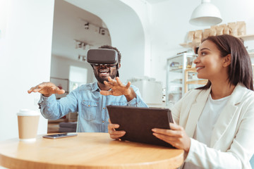 Smiling woman watching her friend test VR headset