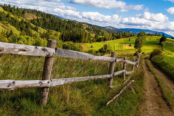 Fototapeta na wymiar Old wooden fence near the mountain road in the Carpathians