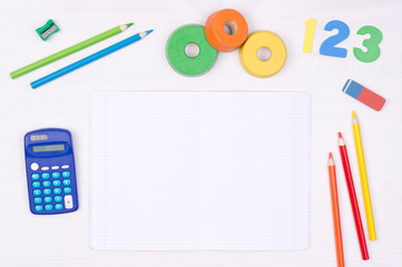 Learning maths. Kid's desk with blank notebook, colorful pencils, numbers and a calculator, top...