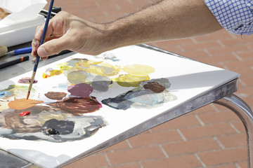 A painter using paint utensils (oil paint, artist brush)