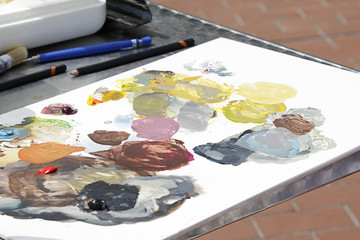 Art palette with oil paints and a brushes on a table