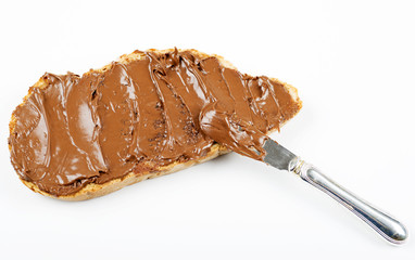 Chocolate spread on bread next to knife on white background. Isolated.