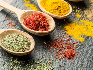 Assortment of colorful spices in the wooden spoons.
