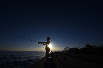 Silhouettes of many fishermen fishing in sea