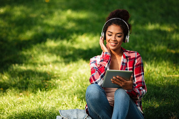 Happy young african woman sitting outdoors in park.