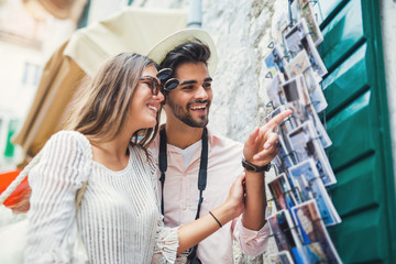 Tourist couple enjoying sightseeing  exploring city and buy postcards