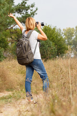 Young lady walking on a rural road with digital camera