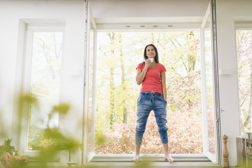 Smiling woman standing in kitchen on windowsill