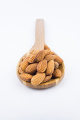 Almonds nuts in wooden ladle isolated on white background. Tasty medicine from nature.