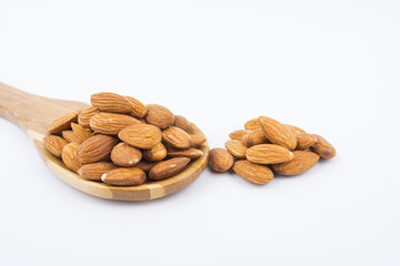 Almonds nuts in wooden ladle isolated on white background. Tasty medicine from nature.