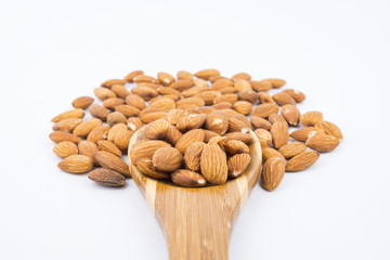 Almonds nuts in wooden ladle isolated on white background. Tasty medicine from nature.