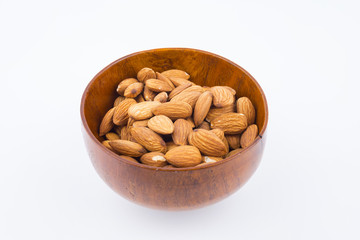 Almonds nuts in wooden bowl isolated on white background. Tasty medicine from nature.