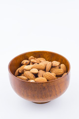Almonds nuts in wooden bowl isolated on white background. Tasty medicine from nature.