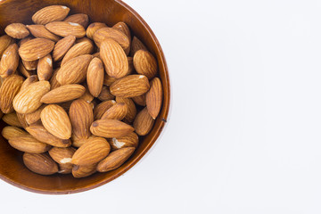 Almonds nuts in wooden bowl isolated on white background. Tasty medicine from nature.