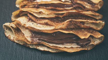 thin crepes or blinis with chocolate cream on slate board