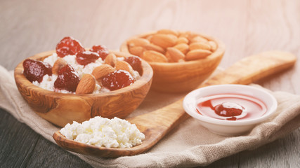 cottage cheese with preserved strawberry in wood bowl on oak table