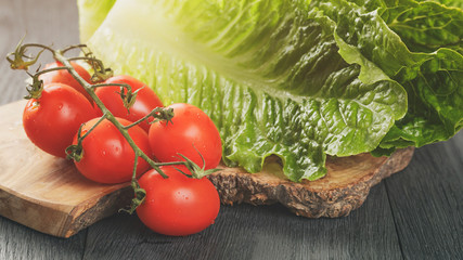 fresh romain green salad and tomatoes on olive board