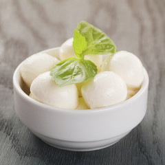 small balls of mozzarella in bowl with basil