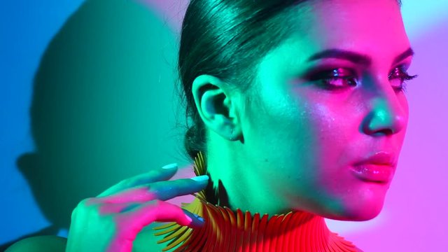 Fashion model woman in colorful bright lights posing in studio, portrait of beautiful sexy girl with trendy make-up and manicure. 4K UHD video 3840x2160