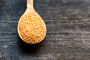 Mustard seeds in wooden spoon close up