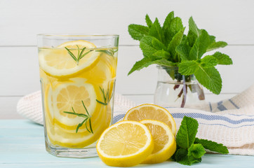 Summer fruit drink on wooden background. Cold lemonade with ice. Detox citrus infused flavored water. Refreshing summer homemade cocktail with lemon. Fresh lemon and lemonade on wooden background