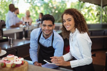 Male waiter and female waitress with digital tablet - obrazy, fototapety, plakaty