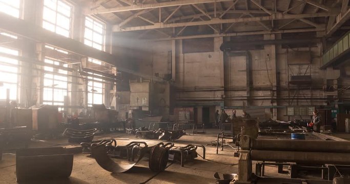Factory beam crane moves on top of a large welding workshop. Workers weld metal structures at plant and move cargo. 4k timelapse video