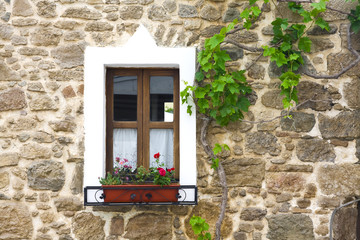 Fototapeta na wymiar old wooden window with flowers on stone wall