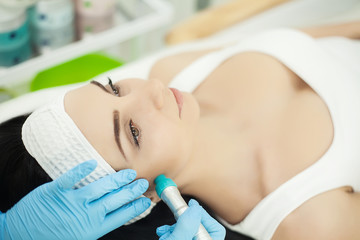 Obraz na płótnie Canvas Girl lying in beauty spa enjoying skin therapy using current treatment