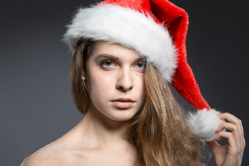 sexy Weihnachtsmädchen mit Mütze vor dunklem Hintergrund