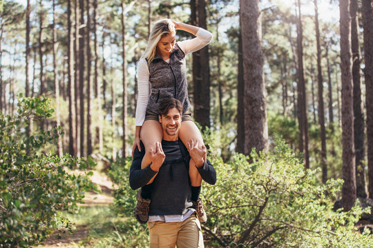 Man carrying his woman partner on his shoulders while trekking i